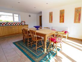 A dining area with a wooden table and chairs on a patterned rug near a kitchen with wooden cabinets at Cedar View in Hainford near Coltishall