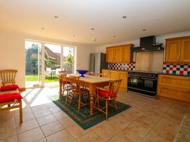 A kitchen with wooden cabinets a dining table and chairs and glass doors leading to a garden at Cedar View in Hainford near Coltishall