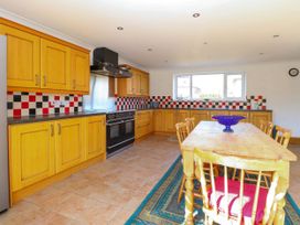A kitchen with wooden cabinets a dining table with chairs and checkered backsplash at Cedar View in Hainford near Coltishall