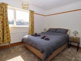 A bedroom with a double bed with gray bedding two bedside tables with lamps and yellow floral curtains at Cedar View in Hainford near Coltishall