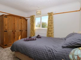 A bedroom with a wooden wardrobe a bed with gray bedding and yellow floral curtains at Cedar View in Hainford near Coltishall