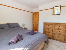 A bedroom with a bed, rolled towels, a bedside table with a lamp, a wooden door, a wooden dresser, and a mirror on the wall at Cedar View in Hainford near Coltishall