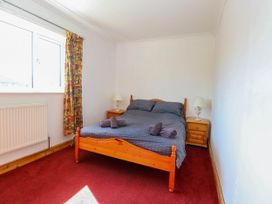 A bedroom with a double bed with gray bedding and towels on a red carpet at Cedar View in Hainford near Coltishall