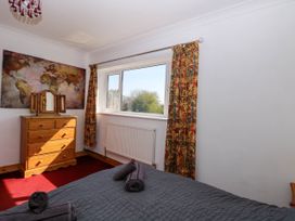 A bedroom with a wooden dresser under a world map and patterned curtains by a window at Cedar View in Hainford near Coltishall