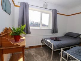 A bedroom with two single beds a wooden desk with a plant and a window with gray curtains at Cedar View in Hainford near Coltishall