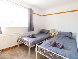 A bedroom with two single beds with grey bedding and towels a nightstand and lamp by a window at Cedar View in Hainford near Coltishall