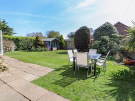 A garden with a glass table and chairs on grass and a small purple shed at Cedar View in Hainford near Coltishall
