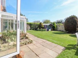 A garden with a lawn a paved patio a small shed and various shrubs at Cedar View in Hainford near Coltishall