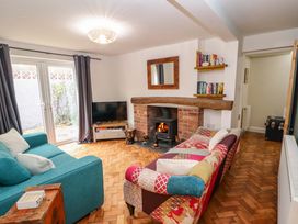 A living room with a patchwork sofa a teal sofa a wood burning stove a television and bookshelves at Seahaven in Allonby