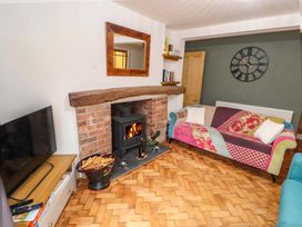 A living room with a wood burning stove fireplace and a colorful sofa at Seahaven in Allonby