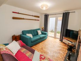A living room with two sofas and a television near a fireplace with paddles on the wall at Seahaven in Allonby