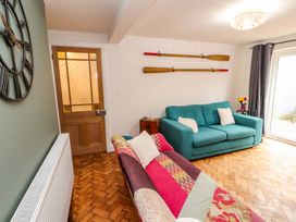 A living room with two sofas a clock on the wall and paddles on the wall at Seahaven in Allonby