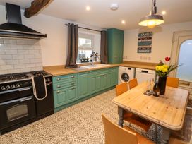 A kitchen with teal cabinets a dining table with chairs and appliances at Seahaven in Allonby