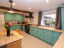 A kitchen with turquoise cabinets a patterned tile floor a wooden table with chairs and a window with gray curtains at Seahaven in Allonby