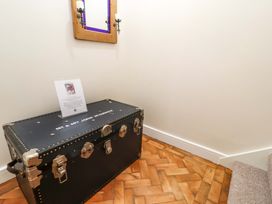 A black trunk with metal locks and a framed sign on top below a mirror with candle holders on a wooden floor at Seahaven in Allonby