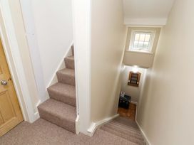 A stairway with carpeted steps and a small window above a hallway at Seahaven in Allonby