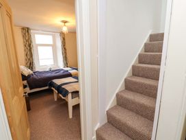 A bedroom with two single beds and a window beside a carpeted staircase at Seahaven in Allonby