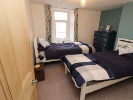 A bedroom with two single beds blue and white blankets a window between the beds and a dresser at Seahaven in Allonby