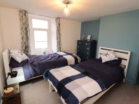 A bedroom with two single beds a chest of drawers and a window with patterned curtains at Seahaven in Allonby