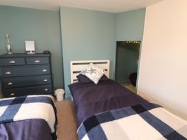 A bedroom with two single beds a blue chest of drawers and a small alcove with lights at Seahaven in Allonby