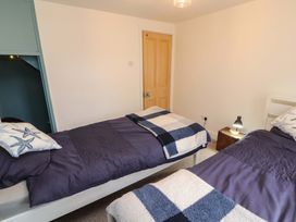 A bedroom with two single beds with blue bedding and starfish pillows at Seahaven in Allonby