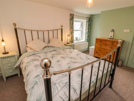 A bedroom with a metal bed frame green bedside tables and a wooden chest of drawers at Seahaven in Allonby