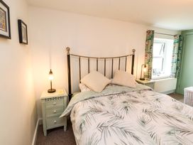 A bedroom with a bed with patterned bedding and two nightstands with lamps at Seahaven in Allonby