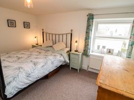 A bedroom with a bed bedside tables lamps a window with curtains and a wooden dresser at Seahaven in Allonby