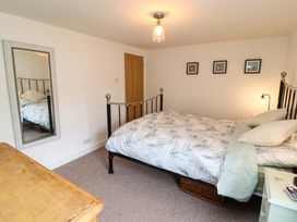 A bedroom with a bed with patterned bedding a wooden dresser a mirror on the wall and three framed pictures at Seahaven in Allonby