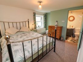 A bedroom with a metal bed frame dresser and an open door to a bathroom at Seahaven in Allonby