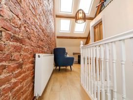 A hallway with a blue chair a white radiator a wooden door and skylights at Seahaven in Allonby