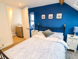 A bedroom with a double bed blue accent wall and bedside tables at Seahaven in Allonby