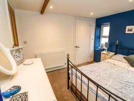 A bedroom with a bed a bedside table and a dresser with a mirror at Seahaven in Allonby