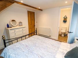 A bedroom with a bed and a dresser next to a wooden door and an ensuite bathroom at Seahaven in Allonby