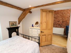 A bedroom with a bed a white dresser a wooden door and exposed wooden beams at Seahaven in Allonby