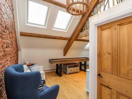 A room with blue and white armchairs a shuffleboard table exposed wooden beams and skylights at Seahaven in Allonby