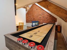 A game room with a shuffleboard table and a chair in front of a brick wall at Seahaven in Allonby
