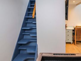A blue staircase with alternating tread design and a wooden handrail next to a white wall and a desk with a wooden chair at Seahaven in Allonby