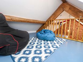A loft space with two bean bags on a rug beside a wooden railing and exposed brick wall at Seahaven in Allonby