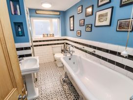 A bathroom with a bathtub sink toilet patterned floor and framed pictures on blue walls at Seahaven in Allonby