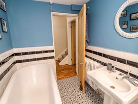 A bathroom with a bathtub a sink a round mirror and blue walls at Seahaven in Allonby
