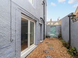 A small outdoor courtyard with gravel flooring a white table and two metal chairs and a green wooden door at Seahaven in Allonby