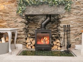 A fireplace with a wood stove and decorative stone wall at The Wonky Nest in Bowness-On-Windermere