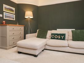 A living room with a sofa, lamp, and dresser at The Wonky Nest in Bowness-On-Windermere