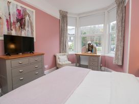 A bedroom with a television, dresser, vanity table, and armchair at The Wonky Nest in Bowness-On-Windermere