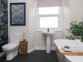 A bathroom with a toilet, sink, bathtub, and a mirror at The Wonky Nest in Bowness-On-Windermere