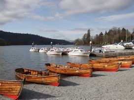 Boats on a lake with a jetty and trees in the background at The Wonky Nest in Bowness-On-Windermere