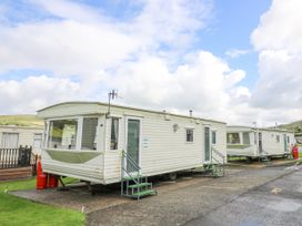 Row of mobile homes with steps leading to doors on a paved area with grassy surroundings at D12 Treetops Clarach near Aberystwyth