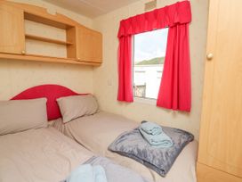 A bedroom with two single beds towels and blankets near a window with red curtains at D12 Treetops Clarach near Aberystwyth