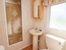 A bathroom with a pedestal sink a toilet a frosted window and a shower with decorative glass at D12 Treetops Clarach near Aberystwyth